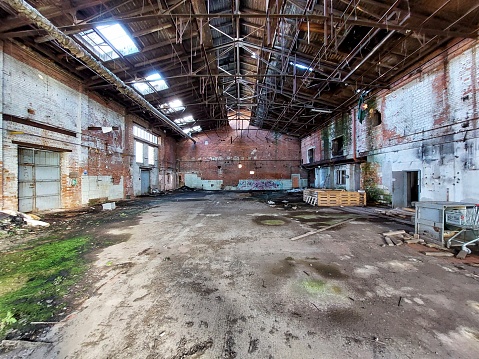 Central perspective of ruined factory hall with debris.