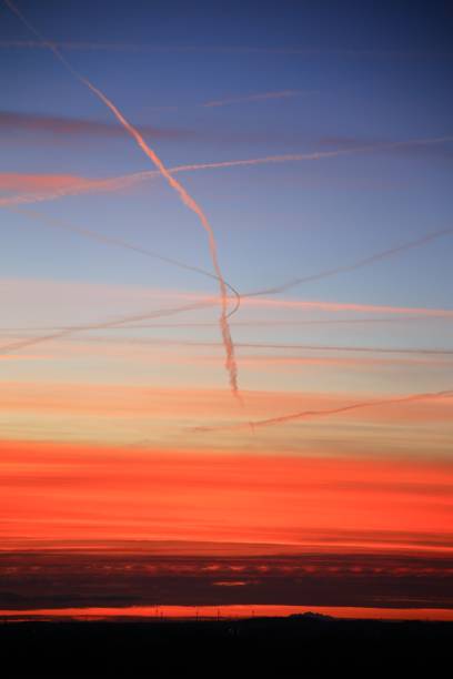 風景のシルエットの上に蒸気の軌跡を持つオレンジ色の夕暮れ - vapor trail cirrus sky cloudscape ストックフォトと画像