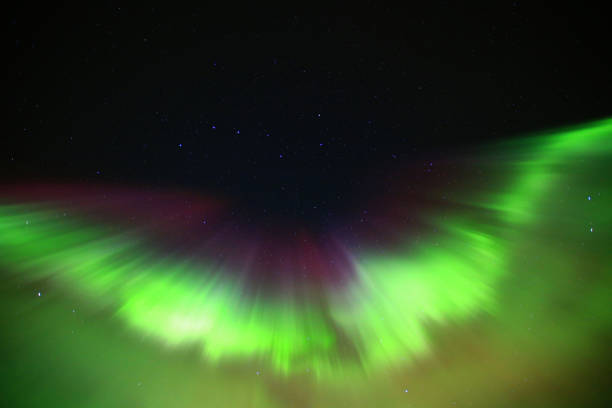 Green and purple aurora formation on starry sky.