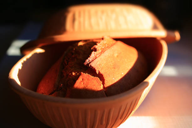 Home baked bread in a traditional clay form with warm sunlight.