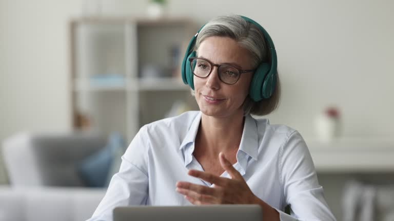 Female wear headphones communicates remotely use video conference app