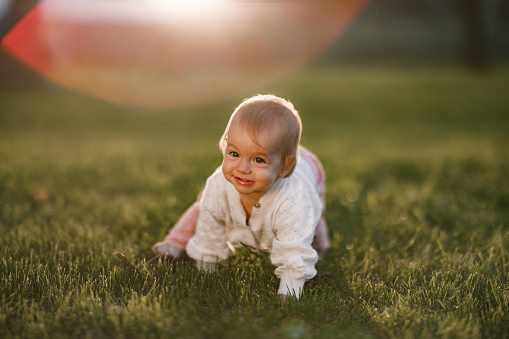 Cute baby girl crawling in public park during sunny day