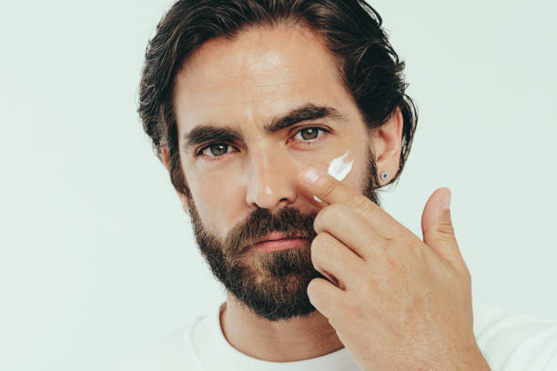 istock Man applying facial cream on his face, keeping it smooth and hydrated 1480270319