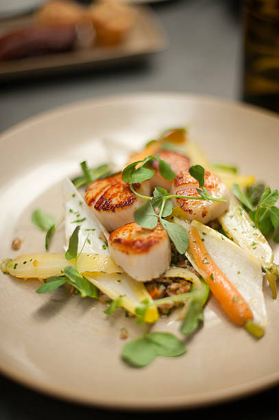 istock Scallops on a plate with watercress, endive, and baby carrots 148027070
