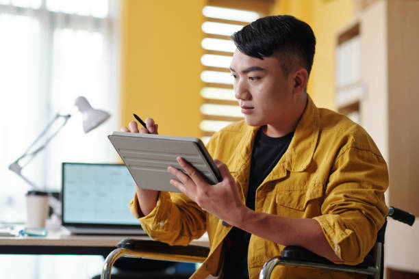 junger mann liest dokument auf tablet - accessability stock-fotos und bilder