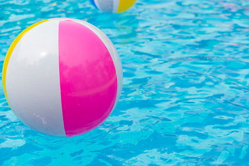 Pink rubber ring with inflatable balls and a ball in the pool