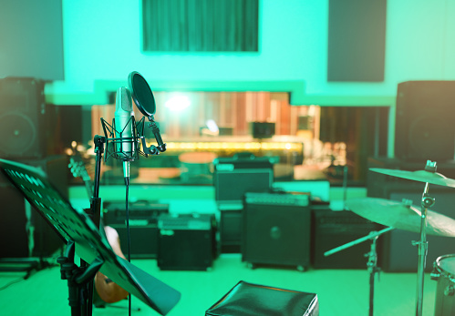 An abstract still life made of the subtle interwoven curves of a classic chrome microphone, an electric guitar, and a vintage wooden radio.