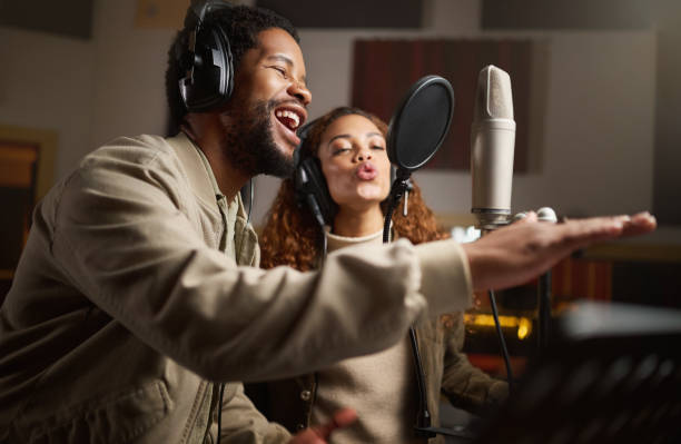 de la musique, un homme et une femme enregistrant en studio à la maison, chantant au micro avec des écouteurs et du talent. groupe ou musicien d’influenceurs technologiques, artistiques et créatifs avec chanson en direct pour la maison de disques. - female likeness audio photos et images de collection