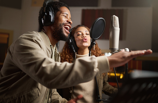 Music, man and woman recording in studio in home, singing into microphone with headphones and talent. Technology, art and creative influencer band or musician with live stream song for record label.