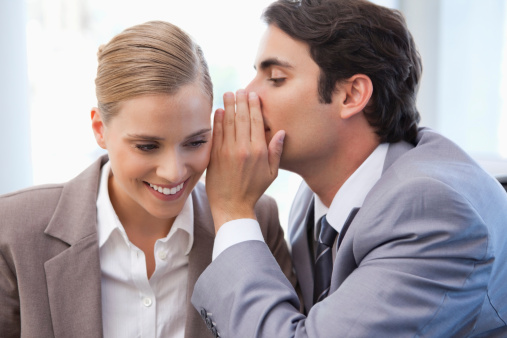 Businessman whispering something to his colleague in a meeting room