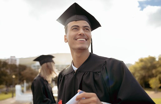A young woman wearing a cap and gown, mixed race Hispanic and Caucasian.  She is a university or high school graduate, smiling at the camera.