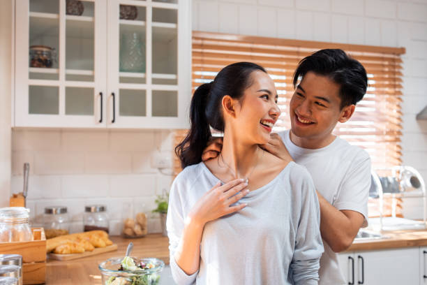istock Asian romantic man making surprise girlfriend with necklace in kitchen. Attractive romantic new marriage couple male and female spend time celebrate anniversary and valentine's day together in house. 1480277732
