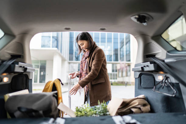 istock Young woman packing her suitcase into the car trunk. 1480278371