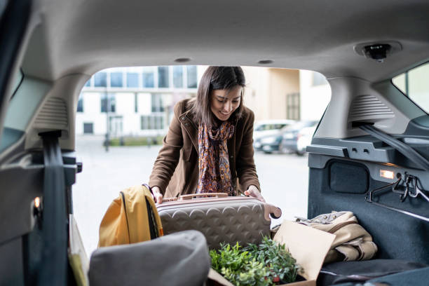 istock Young woman packing her suitcase into the car trunk. 1480278558