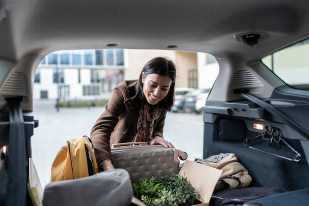 istock Young woman packing her suitcase into the car trunk. 1480278757