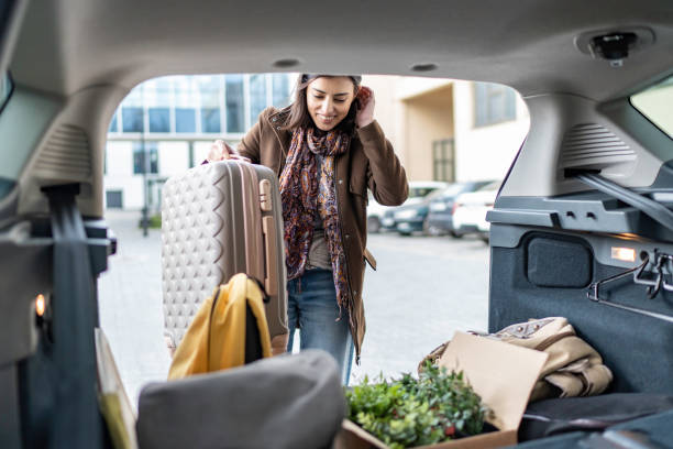 istock Young woman packing her suitcase into the car trunk. 1480278931