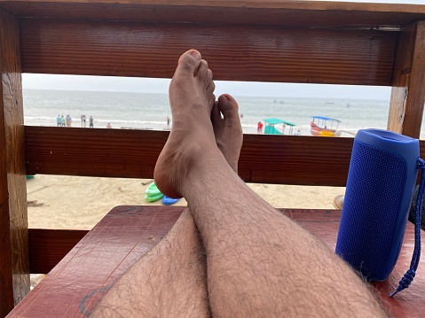 Stock photo showing close-up view of man's feet crossed at ankles on wooden table.