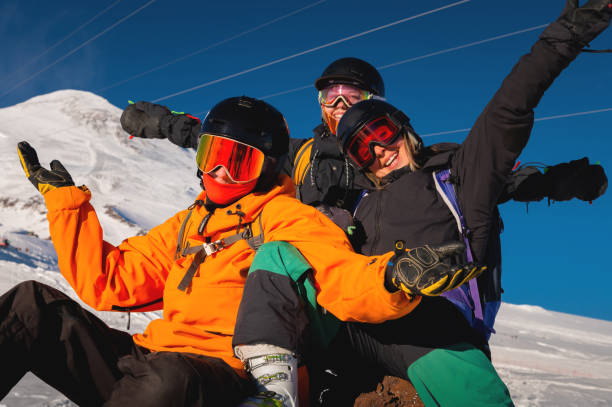 Laughing friends on winter vacation with skiing in snowy mountains, looking at camera. A company of people is enjoying a winter holiday in a ski resort stock photo