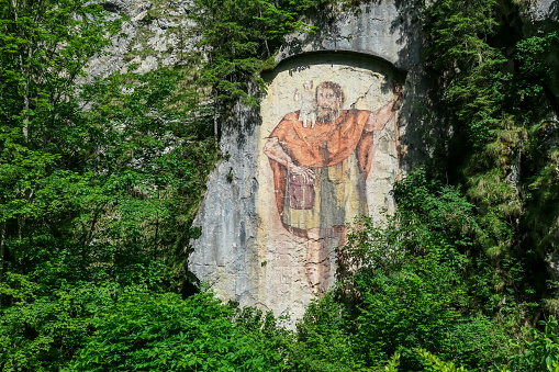 Painting of Saint Christopher and baby Jesus on a rock in Bad Vellach near Bad Eisenkappel, Carinthia, Austria. The rock of Saint Christopher. Religious drawing in a remote mountain valley in the Alps