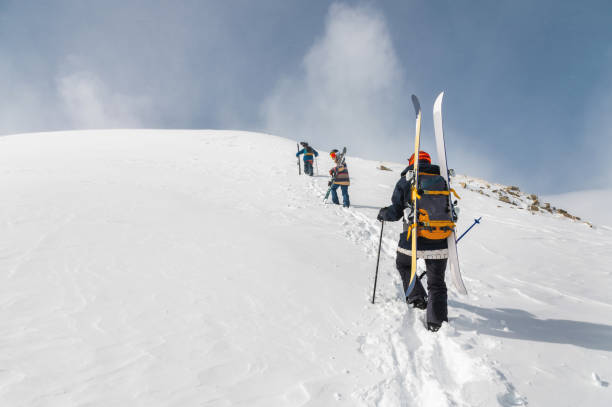 Backcountry climbers, ski climber, walking with skis and snowboard in the mountains. Ski tourism in the alpine landscape. Adventure winter sport stock photo