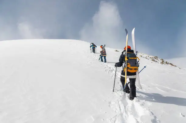 Backcountry climbers, ski climber, walking with skis and snowboard in the mountains. Ski tourism in the alpine landscape. Adventure winter sport.