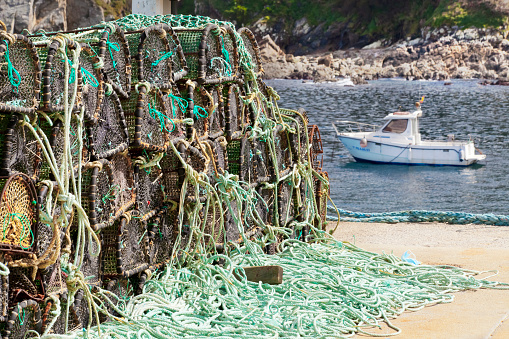 Fishing net baskets on harbor dock, fishing boat . Caión, A Coruña, Galicia, Spain.