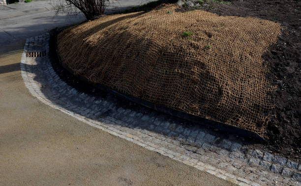 temporäre abdeckung der rasensaat mit textilien, um einen großen hang gegen erosion zu gewährleisten. verwendung von braunem jutegewebe stabilisierendes kokosnussnetz für steile hänge. bei starkem regen sickert der boden nicht aus - erosionskontrolle stock-fotos und bilder