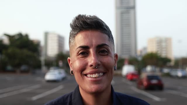 Gay woman looking serious on camera with city in background