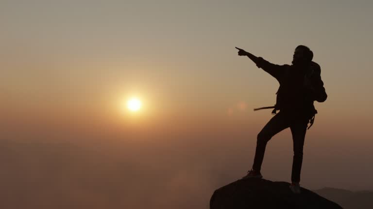 Traveler stand on the rock and pointing to sky