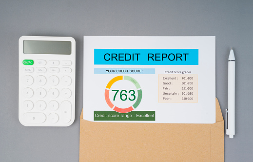 Credit score report and calculator with computer keyboard on the desk.