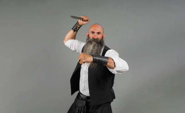 istock a head shaved bearded man holding a knife in attack pose ahead a gray background 1480290618