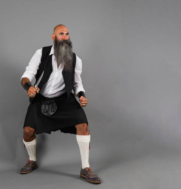 istock a head shaved bearded man performing a warrior standing in battle pose ahead a gray background 1480291421