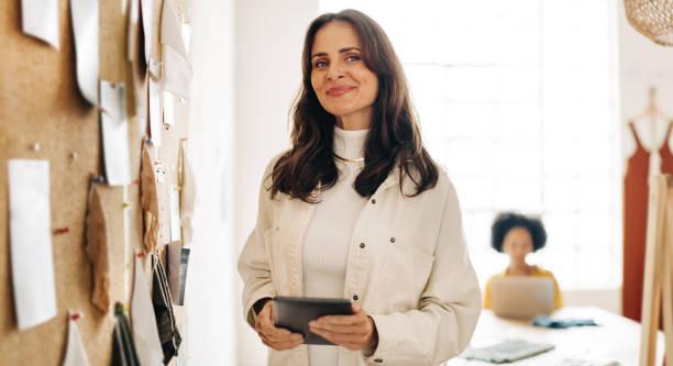 Creative small business owner holding a digital tablet and looking away