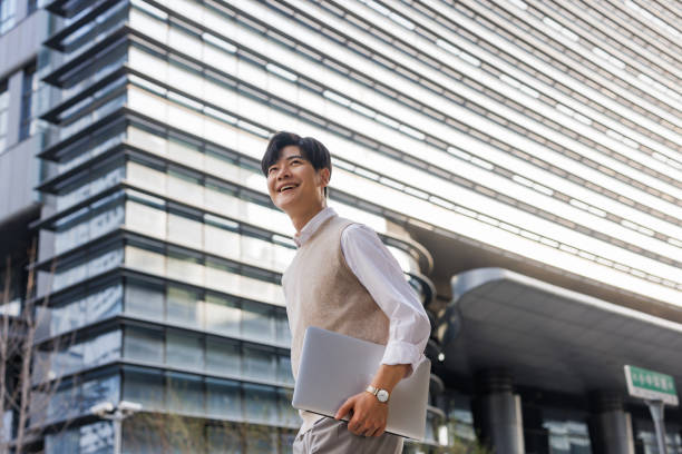 Young white-collar workers walking with laptops in their arms stock photo