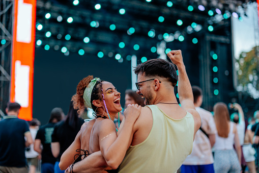 A young content couple is having a great time enjoying the concert on a summer day at a concert.