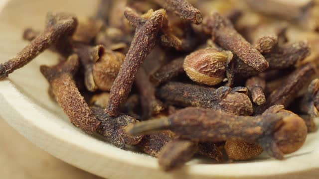 Dry cloves in wooden background. Cloves spice. Close up macro. Slow motion
