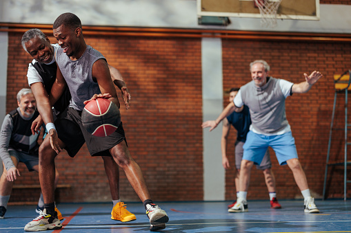 A cheerful group of people are in a gymnasium playing a recreational game of basketball.