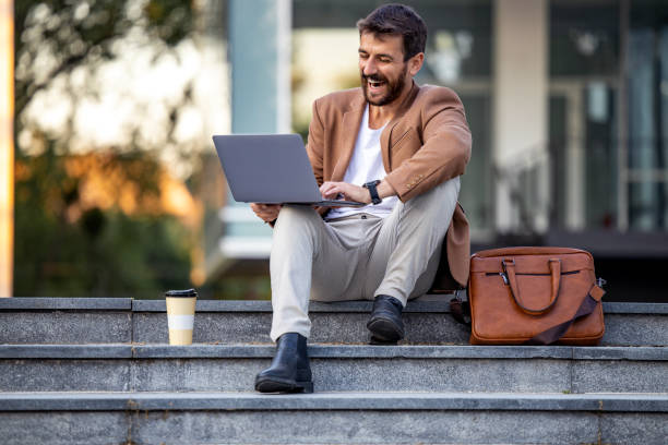 istock Young man sitting on the stairs and using laptop 1480305144