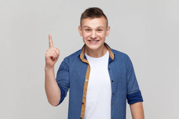 Teenager boy pointing finger up with genius idea, surprised by suddenly invented smart solution.
