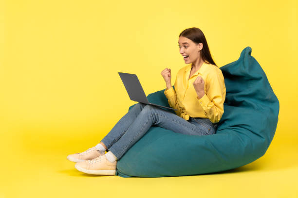 istock Joyful Woman Using Laptop Gesturing Yes Sitting Over Yellow Background 1480307694