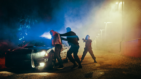 Male Policeman Forcing a Compliant Civilian on the Hood of Police Car. Female Holding Suspect at Gun Point. Officer Violently Pushing Man Against the Car. Shocking Case of Police Brutality.