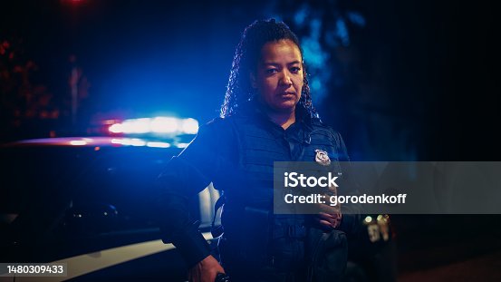 istock Professional Blaсk Female Police Officer Looking at the Camera. Policewoman Maintains public order and safety, Enforcing the Law, Prevents and Investigates Criminal Activity. Cinematic Portrait 1480309433