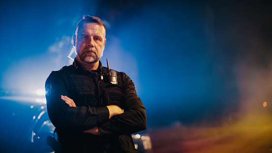 Portrait of a police agent working in the law enforcement against a studio background