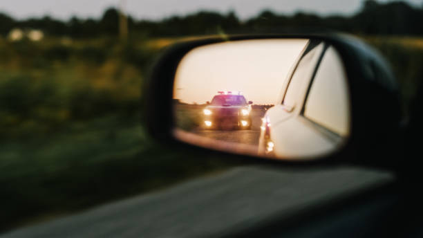 stylish side mirror car chase shot: highway traffic patrol vehicle pull over suspect. professional female police officer approaches vehicle, asks driver license and registration. cinematic shot - speeding ticket imagens e fotografias de stock