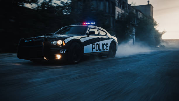 voiture de patrouille de la circulation à sa poursuite. des policiers dans une voiture d’escouade poursuivent un suspect sur industrial road, sirènes flamboyantes, grande vitesse. les flics sur l’appel d’intervention d’urgence. plan d’action ci - véhicule de service durgence photos et images de collection