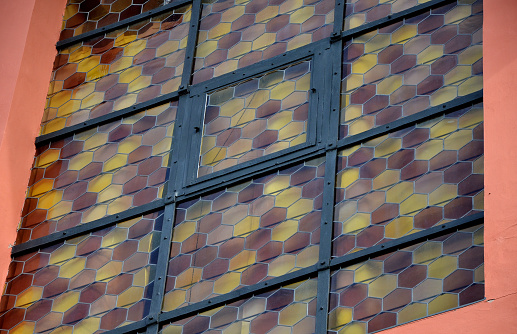 stained glass in the shape of a honeycomb. The lead grid is melted onto the yellow and orange tinted windows. hexagon shapes in black church frame.