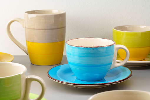 Colorful clay ceramic cups on gray background close up