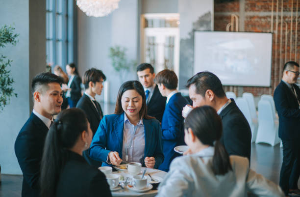 empresários multiétnicos asiáticos falam durante uma pausa para o café na conferência seminar business - event convention center business hotel - fotografias e filmes do acervo