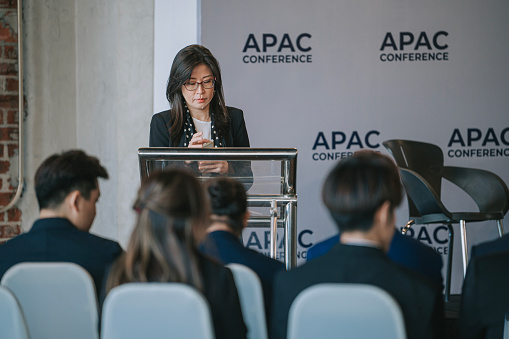 A young Caucasian woman speaking into a microphone at a business conference