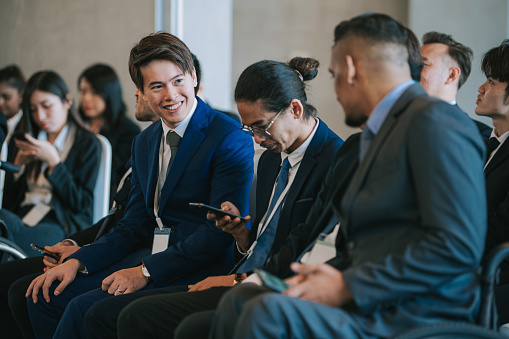 Asian seminar conference participants attending business conference text messaging with phone